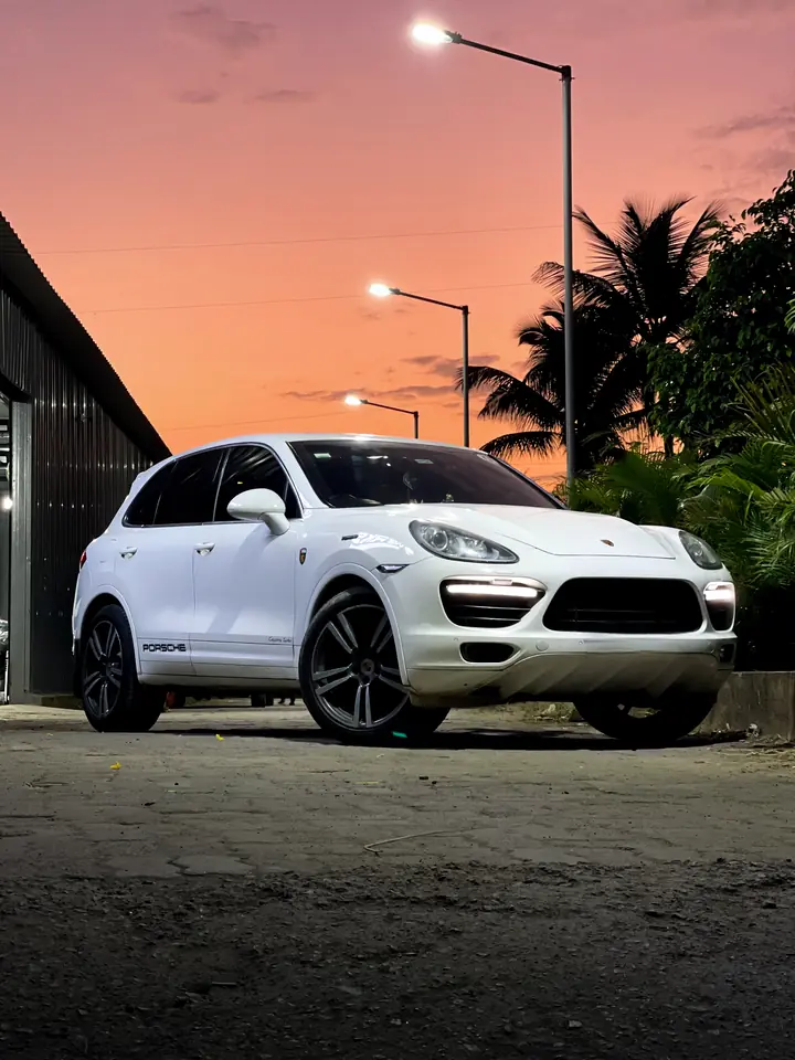 White Porsche SUV outside the workshop at sunset
